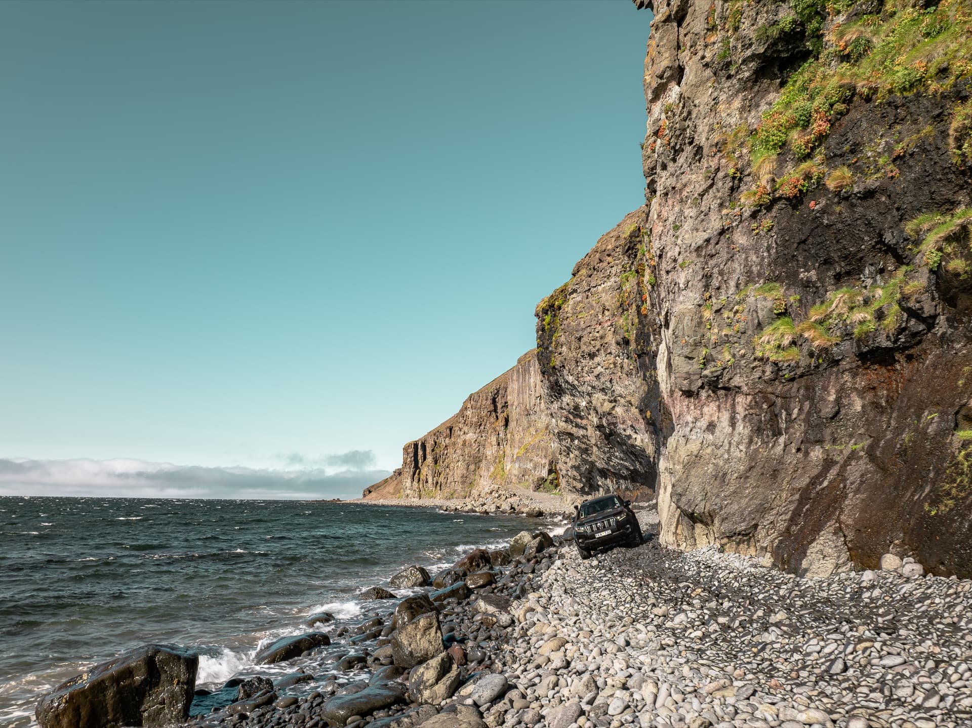 One Luxury Land Cruiser on the Svalvogavegur cliff road beneath sea cliffs in the Westfjords