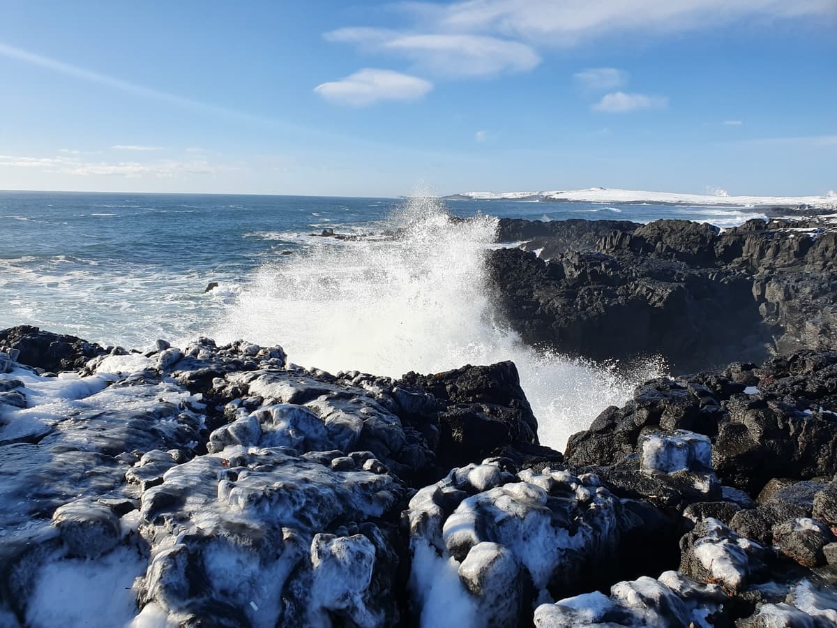 Atlantic waves crashing over ice-covered lava rocks on the Reykjanes coast