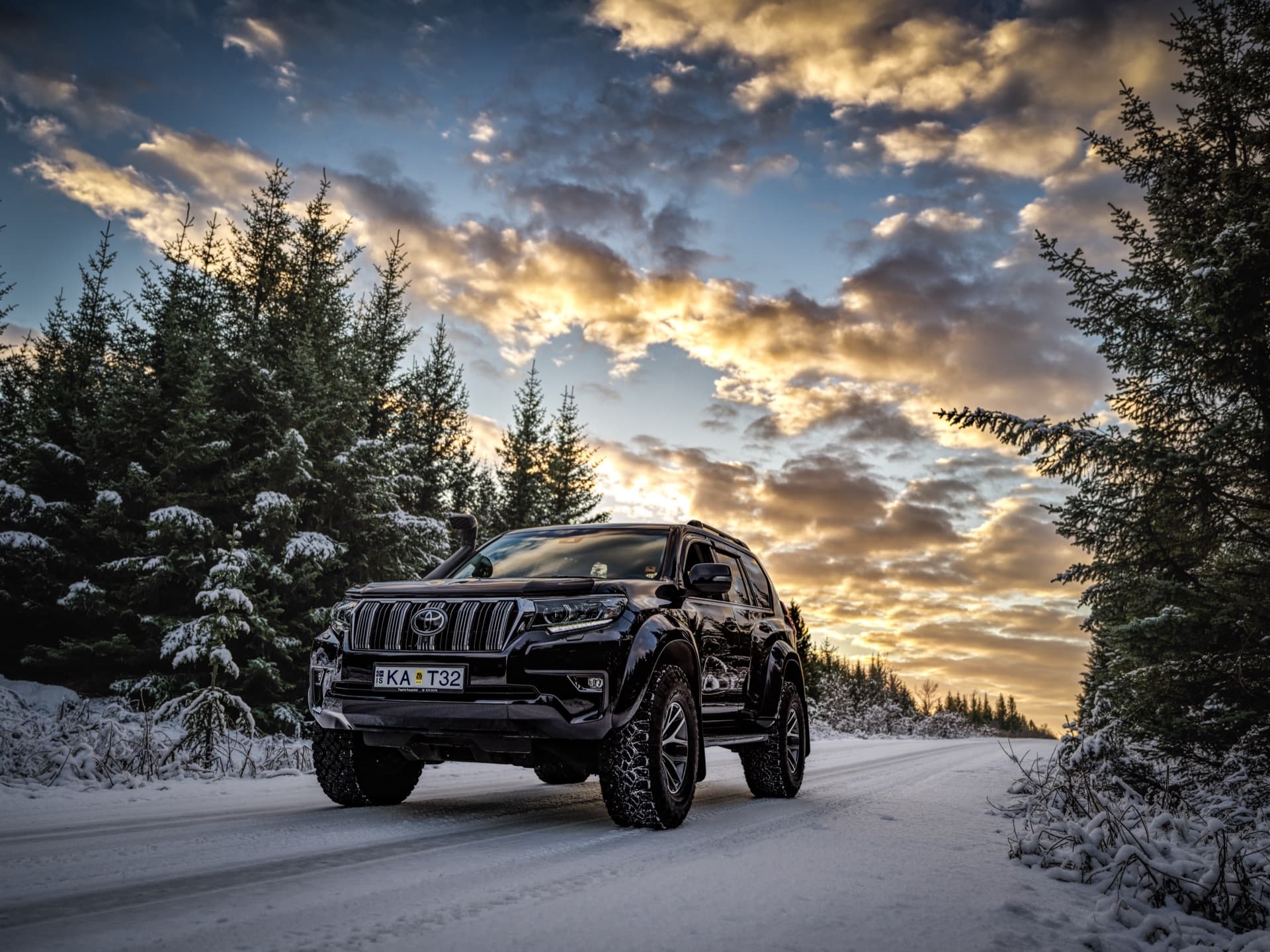 Toyota Land Cruiser VX on a snow-covered forest road at sunset in Iceland