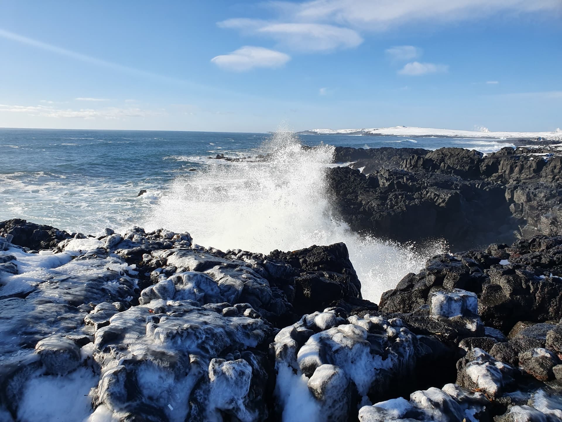 Atlantic waves crashing over ice-covered lava rocks on the Reykjanes coast