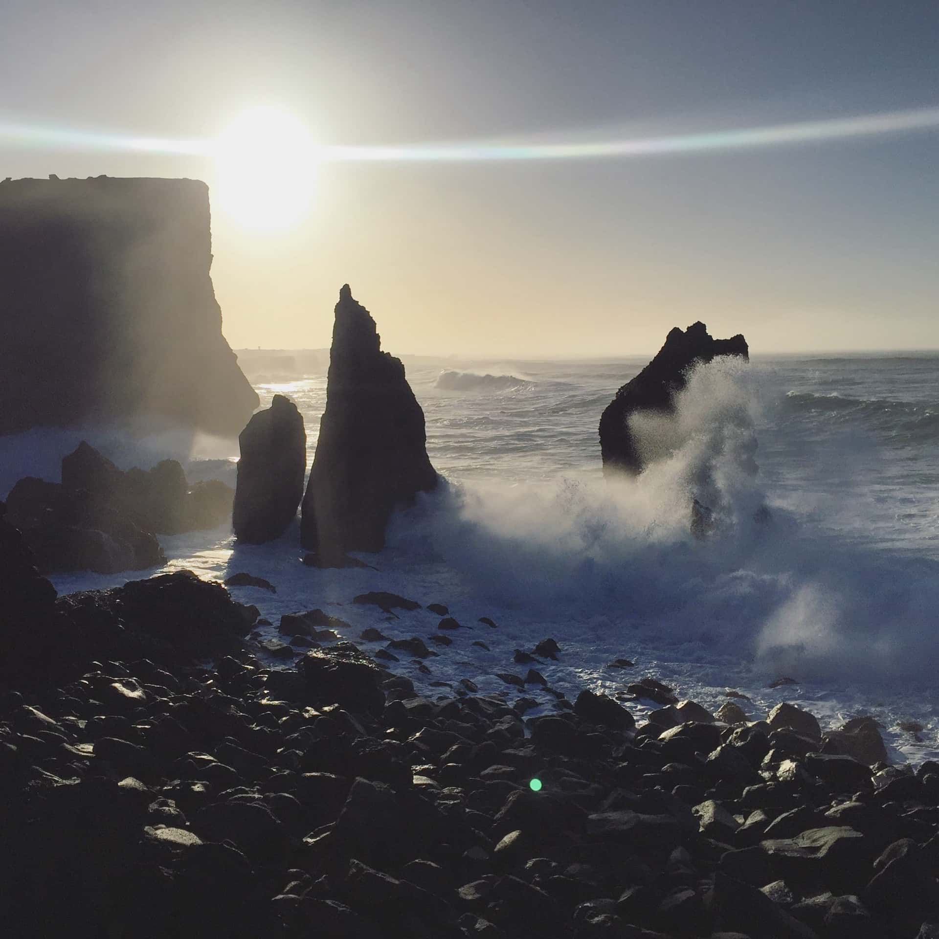 Basalt sea stacks and crashing Atlantic waves on Iceland's volcanic coastline at sunset